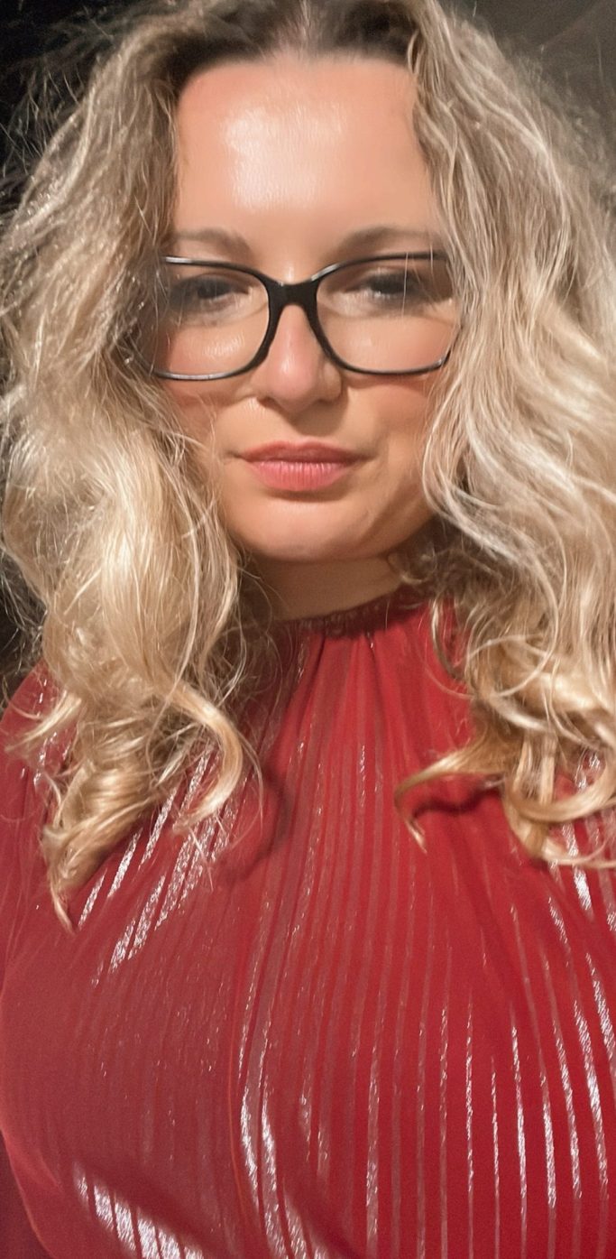 Alina Red Top Fashion designer Alina Koztepe with blonde wavy hair and glasses in a red glossy top